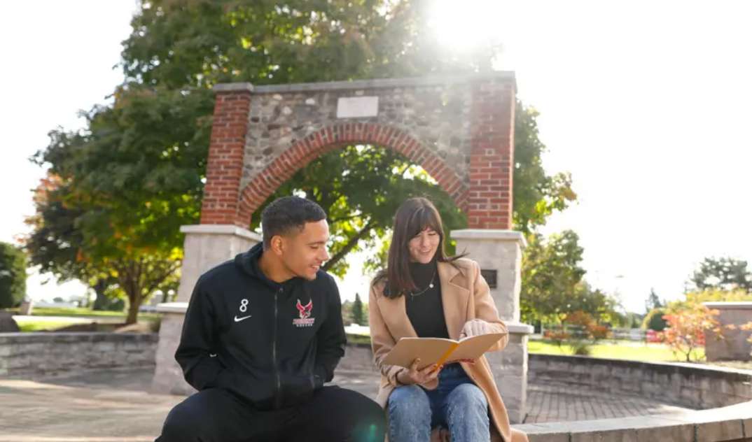 Students seated outside near campus archway