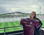 Tori Cleveland smiles holding up soccer jersey