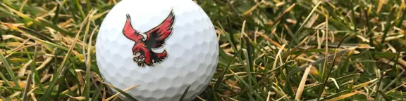 Golf ball with Redhawks logo on grass