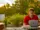 A young man sits with a laptop open and smiles
